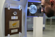 A spectator looks at a tiny piece of moon rock encased in a plastic globe on display at the an exhibition commemorating the 50th anniversary of the last of the U.S. manned missions to the moon and the Artemis spacecraft now orbiting the moon, in Nicosia, Cyprus, Thursday, Dec. 8, 2022. A half century after U.S. astronauts brought it back from the moon's surface, this tiny piece of cosmic rock has finally reached its intended destination, the east Mediterranean island nation of Cyprus. (AP Photo/Petros Karadjias)