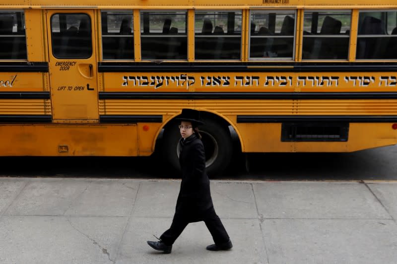 FILE PHOTO: Orthodox Jewish boy walks by a Yeshiva school bus in Brooklyn, New York City