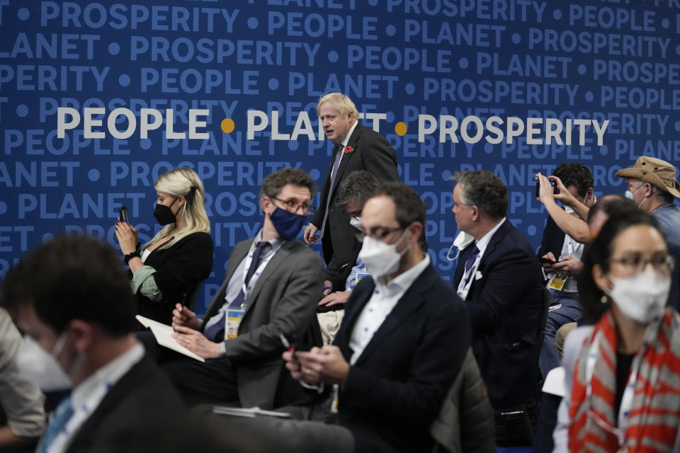 British Prime Minister Boris Johnson walks past a sign reading "People, Planet, Prosperity" as he arrives for a press conference at the La Nuvola conference center for the G20 summit in Rome, Sunday, Oct. 31, 2021. Leaders of the world's biggest economies made a compromise commitment Sunday to reach carbon neutrality "by or around mid-century" as they wrapped up a two-day summit that was laying the groundwork for the U.N. climate conference in Glasgow, Scotland. (AP Photo/Kirsty Wigglesworth)