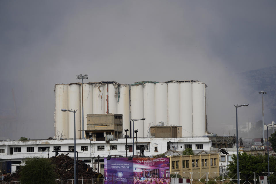 Part of Beirut's massive grain silos, shredded in the 2020 port blast, collapses after a weekslong fire in Beirut, Lebanon, Sunday, July 31, 2022. The northern block of the silos toppled in a huge cloud of dust on Sunday after what sounded like an explosion. (AP Photo/Hassan Ammar)