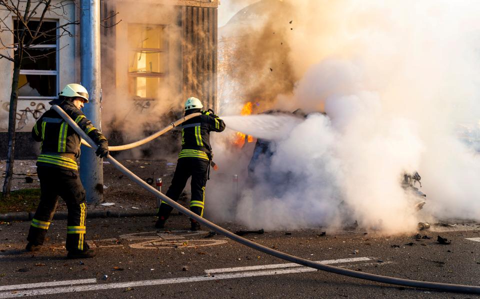 Firefighters try to extinguish a burning car after a Russian attack in Kyiv (AP)