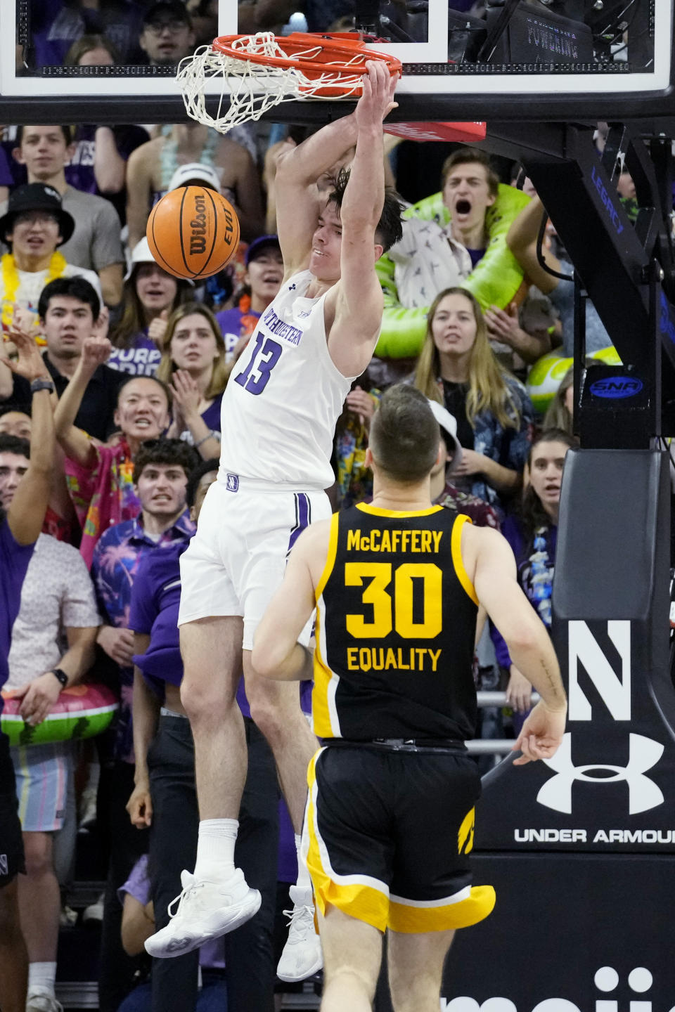 Northwestern guard Brooks Barnhizer (13) dunks as Iowa guard Connor McCaffery looks on during the first half of an NCAA college basketball game in Evanston, Ill., Sunday, Feb. 19, 2023. (AP Photo/Nam Y. Huh)