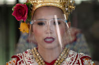 A Thai classical dancer wearing face shield to help curb the spread of the coronavirus performs at the Erawan Shrine in Bangkok, Thailand, Thursday, May 28, 2020. Thai government continues to ease restrictions related to running business in capital Bangkok that were imposed weeks ago to combat the spread of COVID-19. (AP Photo/Sakchai Lalit)