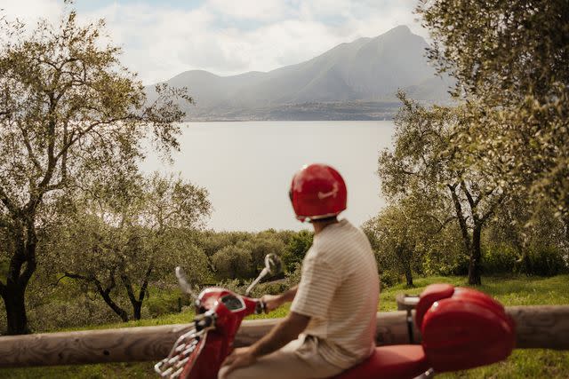 <p>Alex Moling/COURTESY OF Cape of Senses</p> A guest at Cape of Senses driving around Lake Garda on a red vespa