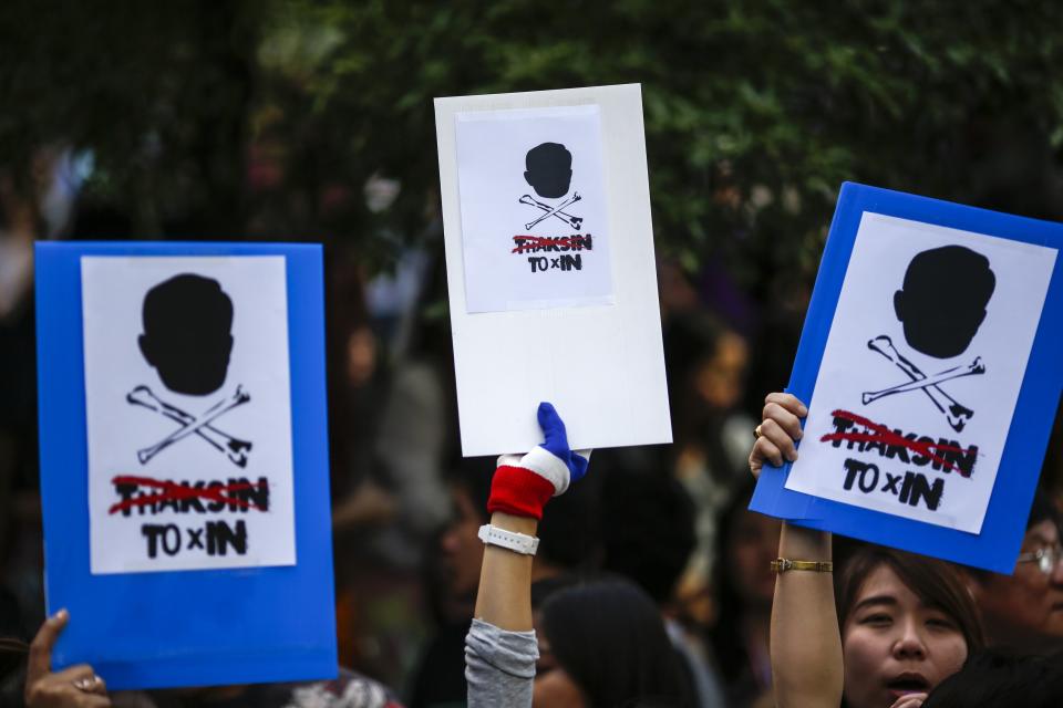 Anti-government protesters hold placards outside the headquarters of the ruling Puea Thai Party of Prime Minister Yingluck Shinawatra in Bangkok