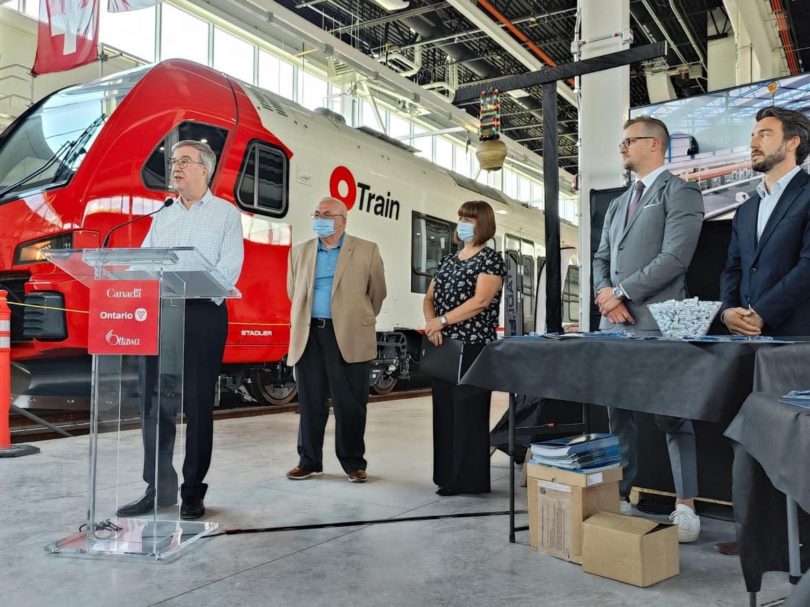 Mayor Jim Watson and other officials — including, from left to right, Coun. Allan Hubley, MP Marie-France Lalonde, Stadler US COO Stefan Baer and TNext project manager Janos Fulde — welcomed the media into the Walkley maintenance and storage facility to view the new Stadler FLIRT train that will operate on the Trillium Line when it's completed. (Reno Patry/CBC - image credit)