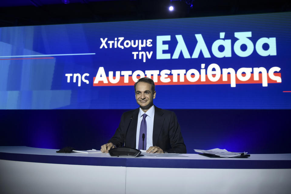 Greece's Prime Minister Kyriakos Mitsotakis waits for a news conference to start in the northern city of Thessaloniki, Greece, Sunday, Sept. 13, 2020. Mitsotakis outlined plans Saturday to upgrade the country's defense capabilities, including purchases of new fighter planes, frigates, helicopters and weapons systems, amid heightened tensions with neighboring Turkey over rights to resources in the eastern Mediterranean. The sign reads : " We build a self-confident Greece". (AP Photo/Giannis Papanikos)