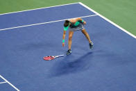 Alize Cornet, of France, picks her racket she tossed during a match with Emma Raducanu, of Britain, at the first round of the US Open tennis championships, Tuesday, Aug. 30, 2022, in New York. (AP Photo/Frank Franklin II)