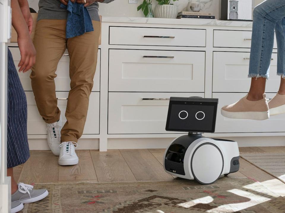 Amazon Astro robot on kitchen floor surrounded by people talking