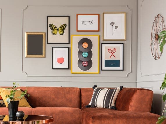 brown sectional couch with gallery wall above and plants