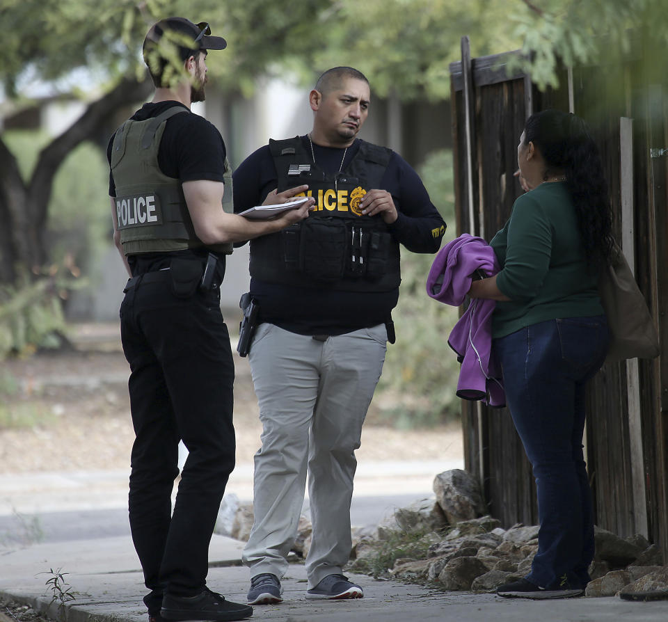 Law enforcement personnel talk to residents in the neighborhood as they continue their investigation at the scene following a shooting Friday, Nov. 30, 2018, in Tucson, Ariz. A deputy U.S. marshal serving a felony arrest warrant was shot and killed outside the Tucson house the night before. The suspect was arrested after an hour-long standoff at the home. (Ron Medvescek/Arizona Daily Star via AP)