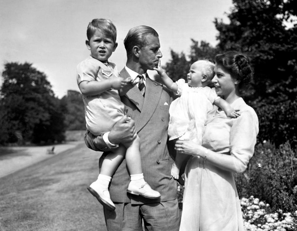 Princess Anne in the arms of Princess Elizabeth, with the Duke of Edinburgh, holding Prince Charles, in the grounds of Clarence House, their London residence. (PA)