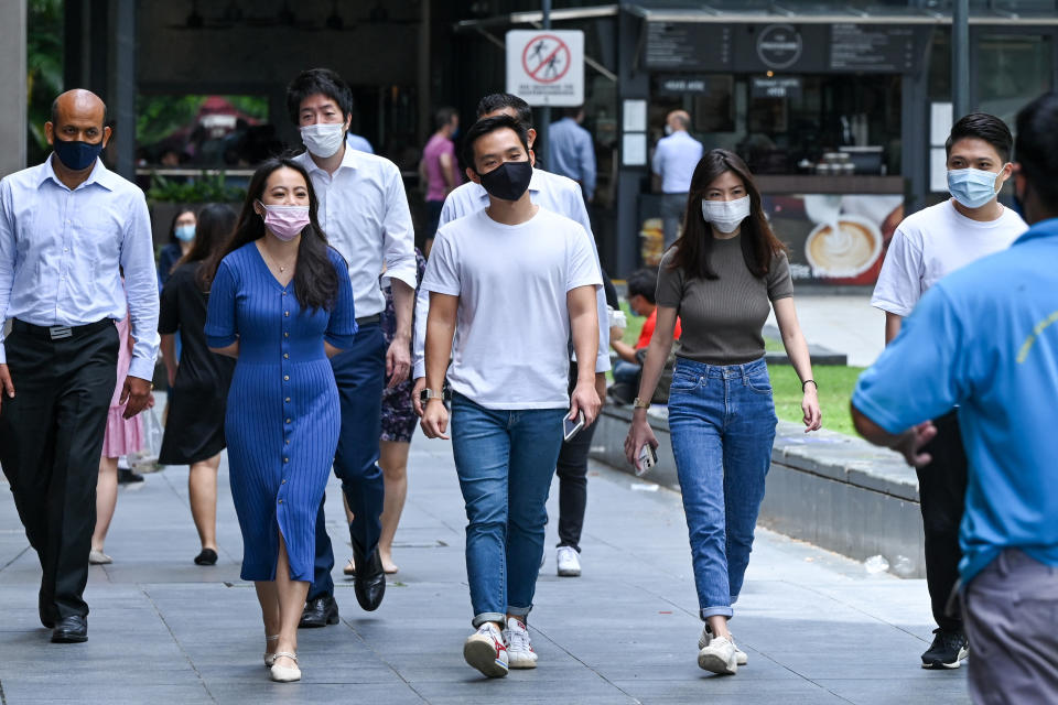 In this photograph taken on February 18, 2022, office workers go out for their lunch break in the Raffles Place financial business district in Singapore. - Rivals Singapore and Hong Kong have become pandemic polar opposites, the former opting to live with the coronavirus and reopen to the world while the latter doubles down on zero-Covid and its international isolation. - To go with AFP story Health-virus-Hong Kong-China-Singapore, FOCUS by Holmes Chan with Catherine Lai in Singapore (Photo by Roslan RAHMAN / AFP) / To go with AFP story Health-virus-Hong Kong-China-Singapore, FOCUS by Holmes Chan with Catherine Lai in Singapore (Photo by ROSLAN RAHMAN/AFP via Getty Images)
