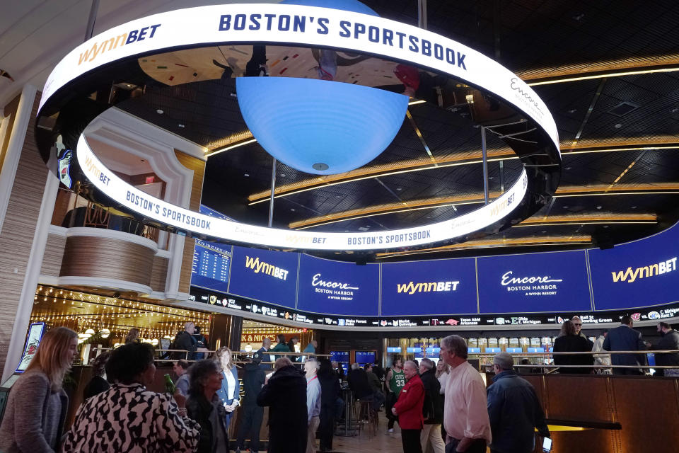 A sign, above, calls attention to sports betting at Encore Boston Harbor casino, Tuesday, Jan. 31, 2023, in Everett, Mass. Massachusetts sports fans who want to wager on their favorite teams are finally getting their chance as the state kicks off sports betting at casinos in the state beginning Tuesday, Jan. 31, with online betting likely to follow in a few months. (AP Photo/Steven Senne)