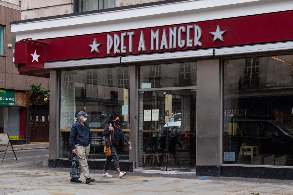 People wearing protective face masks walk past a closed branch of Pret a Manger in central London, after the sandwich chain announced it is to permanently shut 30 of its stores after footfall was hammered by the coronavirus lockdown. (Photo by Dominic Lipinski/PA Images via Getty Images)