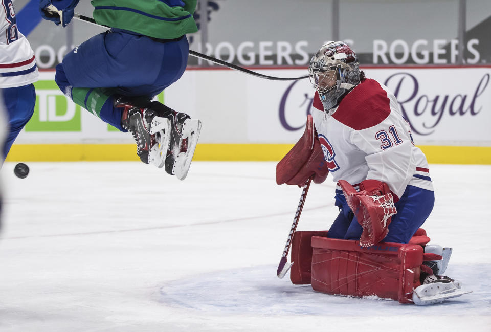 Montreal Canadiens goalie Carey Price makes a save as Vancouver Canucks' Brock Boeser jumps in front of him during the second period of an NHL hockey game Saturday, Jan. 23, 2021, Vancouver, British Columbia. (Darryl Dyck/The Canadian Press via AP)