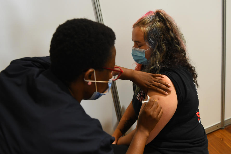 Paramedic Rhiannon Gallatly (right) receives a AstraZeneca covid19 vaccination at the Royal Exhibition Centre in Melbourne. Source: AAP