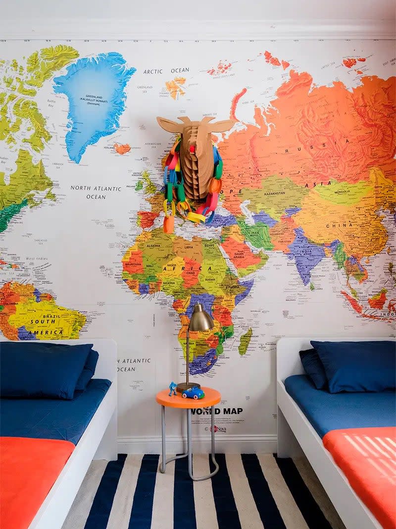 Kids' room with striped rug and big, colorful world map along back wall. 