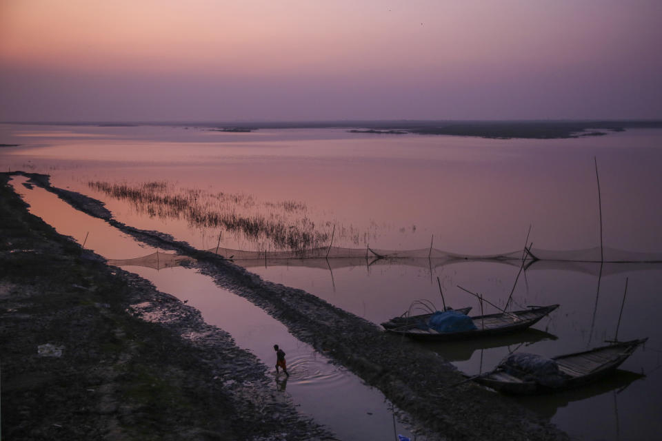 An Indian fisherman wades through shallow waters to reach the banks of the river Ganges after sundown in Bhagalpur in the eastern Indian state of Bihar, Wednesday, Nov. 13, 2019. For more than 1,700 miles, stretching from the Gangotri Glacier in the Himalayas to the Bay of Bengal, the Ganges flows across the plains like a timeline of India's past, nourishing an extraordinary wealth of life. It has seen empires rise and fall. It has seen too many wars, countless kings, British colonials, independence and the rise of Hindu nationalism as a political movement. (AP Photo/Altaf Qadri)