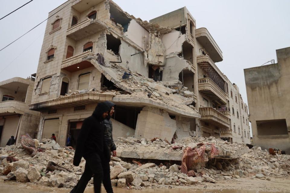 Two men walk past a heavily damaged building following an earthquake in the town of Zardana in the countryside of the northwestern Syrian Idlib province (AFP via Getty Images)