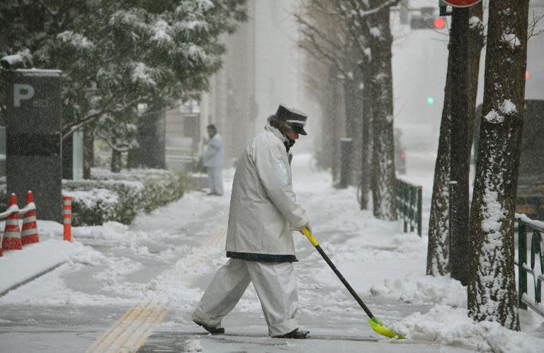 A worker removes snow from a sidewalk in Tokyo on February 8, 2014