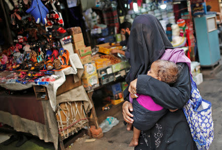 A veiled Muslim woman holds her baby as she walks through a street in the old quarters of Delhi, India May 1, 2019. REUTERS/Adnan Abidi