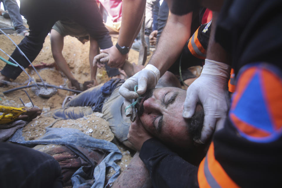 Palestinians rescue a wounded man from the rubble of a destroyed building following an Israeli airstrike in Rafah, Gaza Strip, Friday, Oct. 13, 2023. (AP Photo/Hatem Ali)