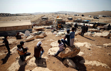 People watch as an Israeli vehicle demolishes Palestinian dwellings in Abu Nuwar village in the occupied West Bank July 4, 2018. REUTERS/Mohamad Torokman