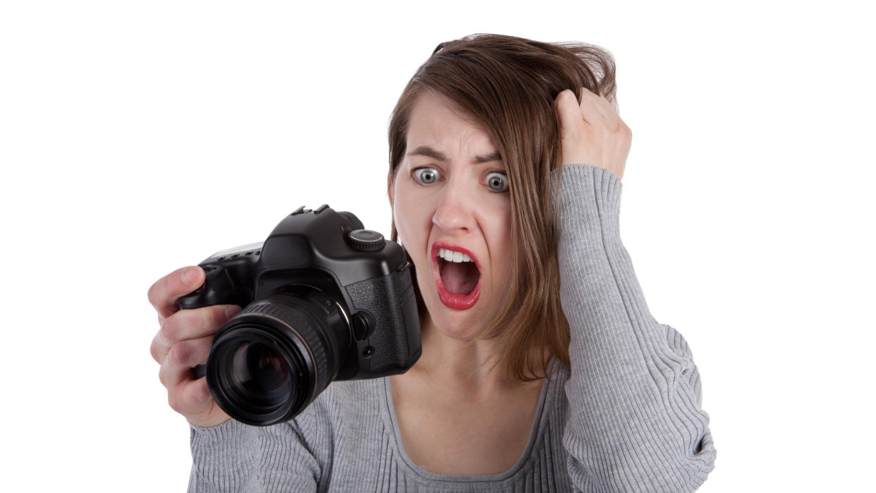  A frustrated photographer pulling her hair out as she reads the display screen on the back of her digital SLR camera. 