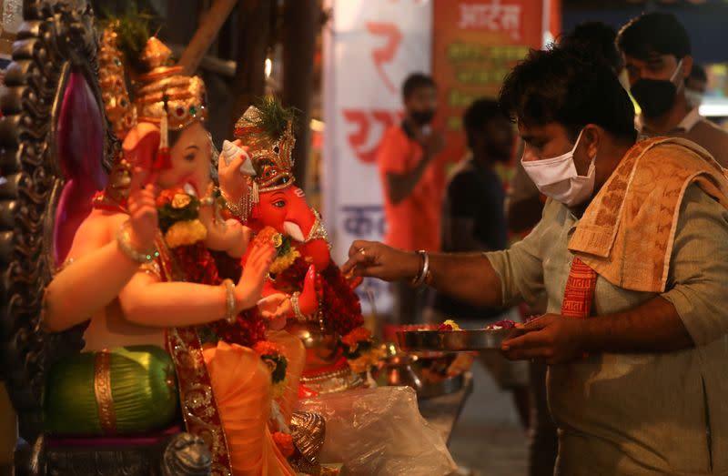 A Hindu priest wearing a protective face mask conducts a puja in front of idols of Hindu God Ganesh, the deity of prosperity, before they can be taken home ahead of the Ganesh Chaturthi festival in Mumbai