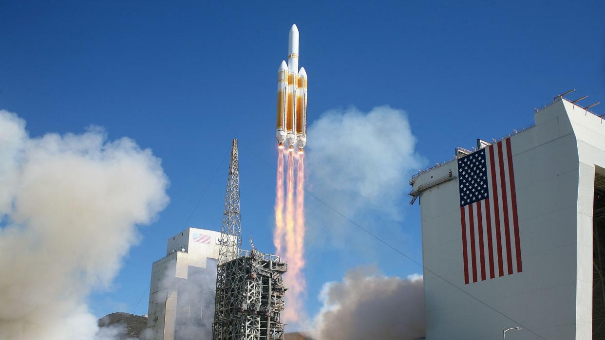  A white rocket blasts off during the day, leaving a streak of fire behind it. 