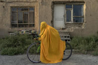 An Afghan woman poses for a photo with her bicycle in Kabul, Afghanistan, Monday, Sept. 19, 2022. The ruling Taliban have banned women from sports as well as barring them from most schooling and many realms of work. A number of women posed for an AP photographer for portraits with the equipment of the sports they loved. Though they do not necessarily wear the burqa in regular life, they chose to hide their identities with their burqas because they fear Taliban reprisals and because some of them continue to practice their sports in secret. (AP Photo/Ebrahim Noroozi)