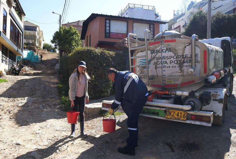 Una mujer junta agua potable de un camión cisterna en La Calera, cerca de Bogotá, el 10 de abril de 2024. 