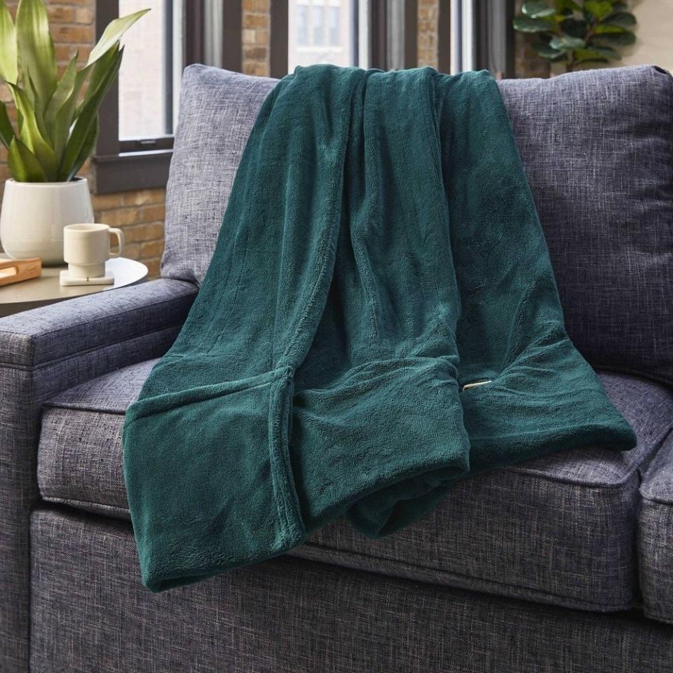 Plush green blanket draped over a couch, adding comfort to home decor. Perfect for cozy shopping finds