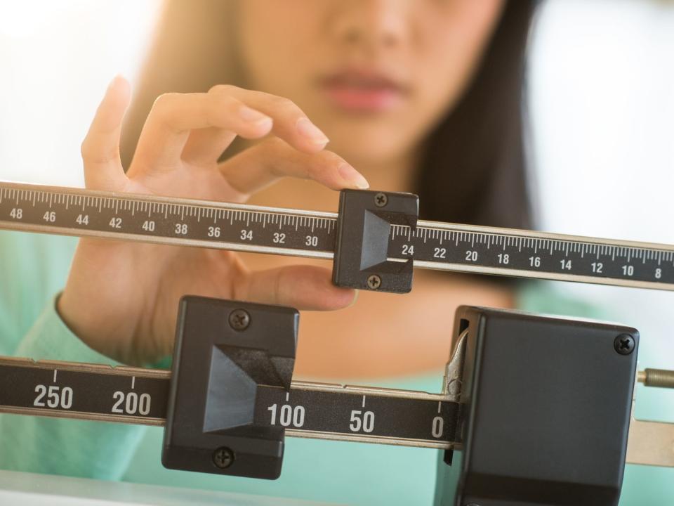 A woman adjusting a scale checking weight, weight loss