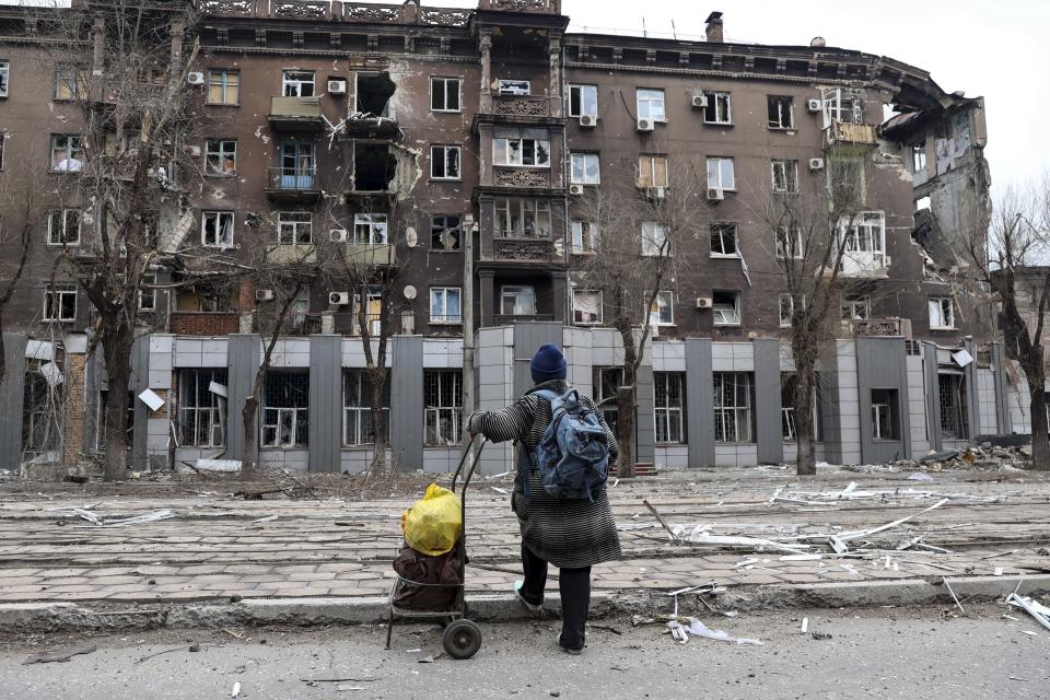 A local resident looks at a damaged during a heavy fighting apartment building near the Illich Iron & Steel Works Metallurgical Plant, the second largest metallurgical enterprise in Ukraine, in an area controlled by Russian-backed separatist forces in Mariupol, Ukraine, Saturday, April 16, 2022. Mariupol, a strategic port on the Sea of Azov, has been besieged by Russian troops and forces from self-proclaimed separatist areas in eastern Ukraine for more than six weeks. (AP Photo/Alexei Alexandrov)