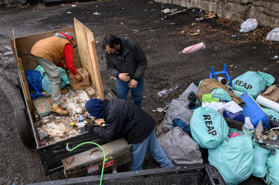 Paula Riethmiller and volunteers Gene and Michael dispose of trash found in encampments at the city dump in Wheeling on Dec. 21. Riethmiller helps lead Trash Talkers, an operation formed during the pandemic by the unhoused to solve trash accumulation in their tent encampments. Unhoused volunteers can earn gift cards and items such as phones through their volunteerism with the program.<span class="copyright">Rebecca Kiger</span>