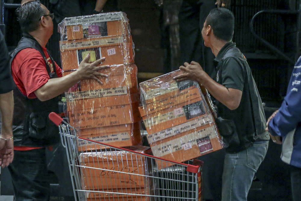 Investigators lift sealed boxes believed to contain luxury designer bags onto a Black Maria outside Pavilion Residences in Kuala Lumpur May 18, 2018. — Picture by Hari Anggara