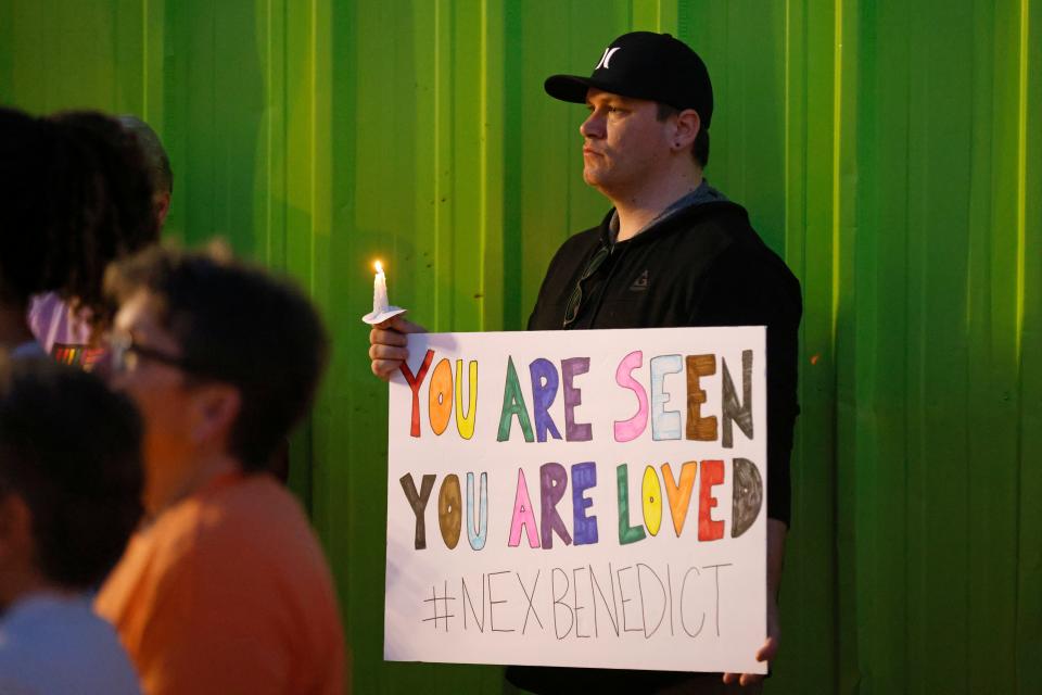 Kody Macaulay holds a sign during a candlelight service for Nex Benedict on Saturday at Point A Gallery, 2124 NW 39 in Oklahoma City.
