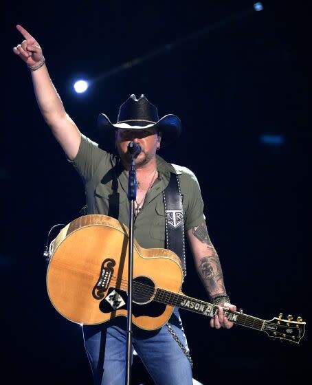 Onstage with his guitar, Jason Aldean points his finger to the sky