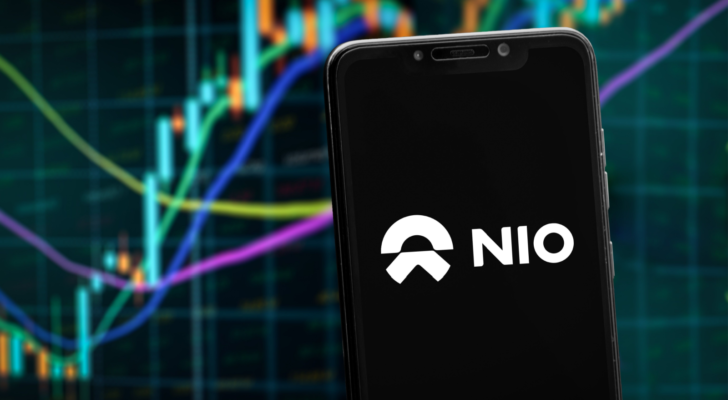 NIO logo on the smartphone screen and the chart of stock market at the blurred background.