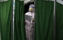 Nhuja Kaiju, of the RNA-16 volunteer group, wearing protective suit calls out for a patient as she helps collect swab samples in Bhaktapur, Nepal, Tuesday, May 26, 2020. RNA-16 stands for “Rescue and Awareness” and the 16 kinds of disasters they have prepared to deal with, from Nepal’s devastating 2015 earthquake to road accidents. But the unique services of this group of three men and a woman in signature blue vests in the epidemic amount to a much greater sacrifice, said doctors, hospital officials and civic leaders. (AP Photo/Niranjan Shrestha)