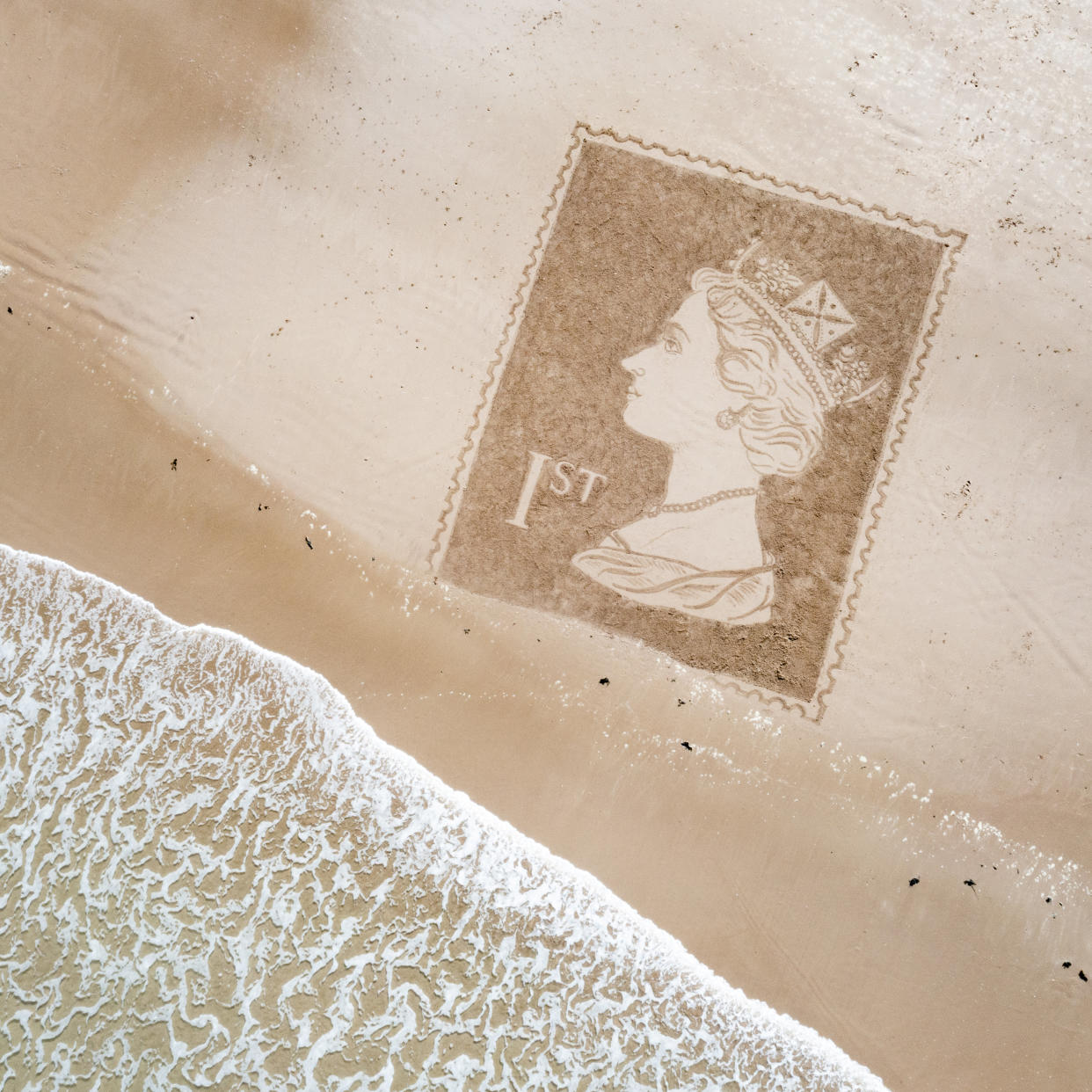 A first class stamp with a portrait of the Queen made using a rake on Bamburgh beach in Northumberland. (SWNS)