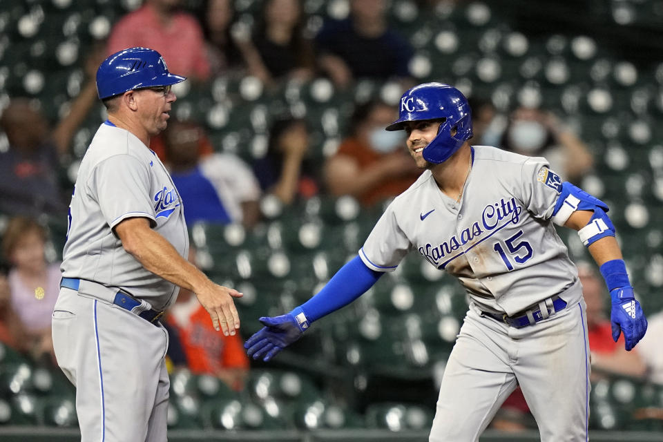 Kansas City Royals' Whit Merrifield (15) celebrates with third base coach Vance Wilson after hitting a two-run triple against the Houston Astros during the eighth inning of a baseball game Monday, Aug. 23, 2021, in Houston. (AP Photo/David J. Phillip)