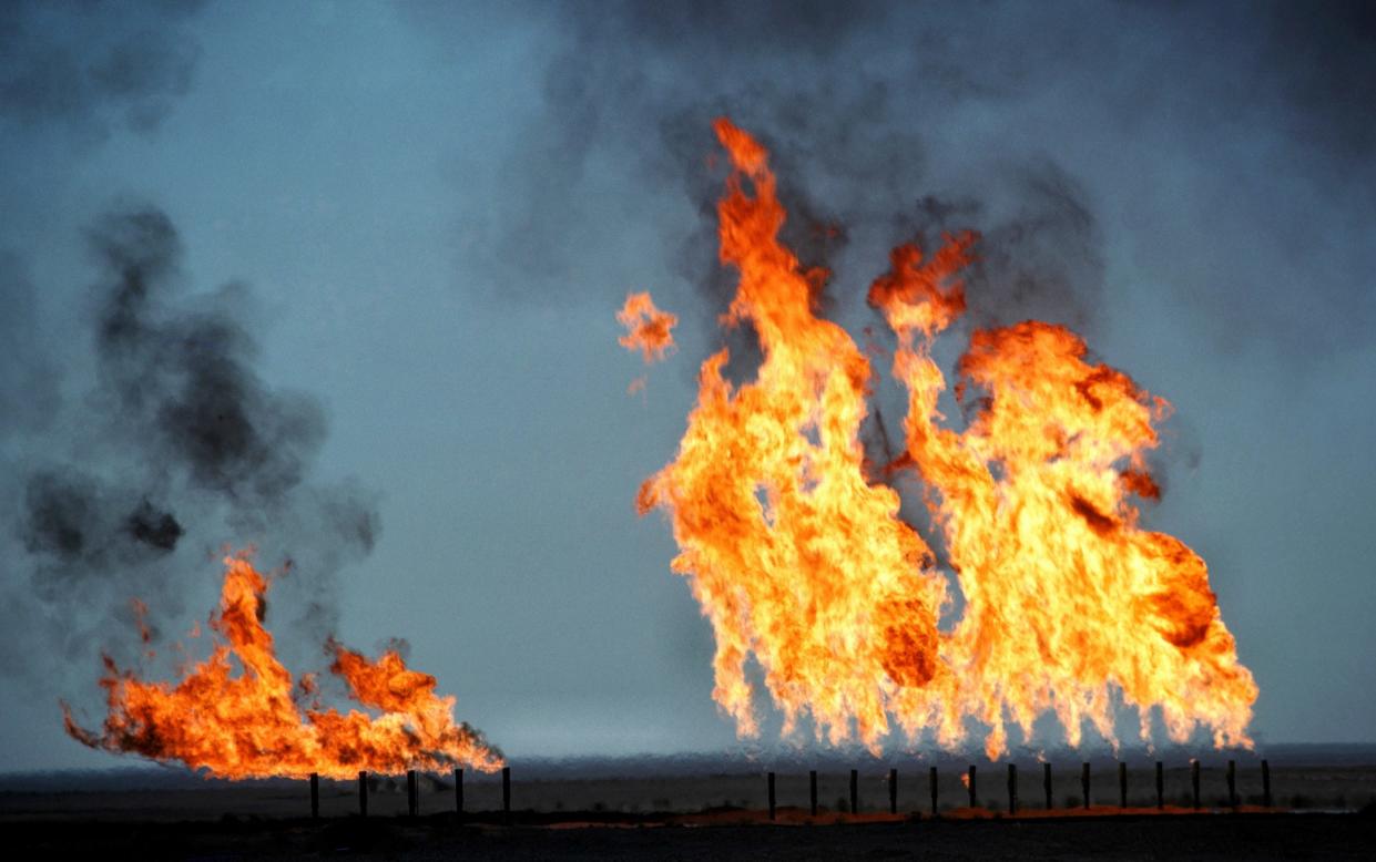 Flames rise high in a flat landscape, with black smoke issuing