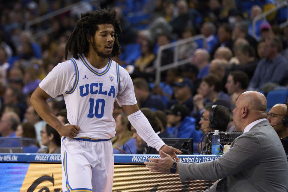 UCLA guard Tyger Campbell (10) is greeted by assistant coach Darren Savino during the first half of the team's NCAA college basketball game against California on Saturday, Feb. 18, 2023, in Los Angeles. (AP Photo/Allison Dinner)