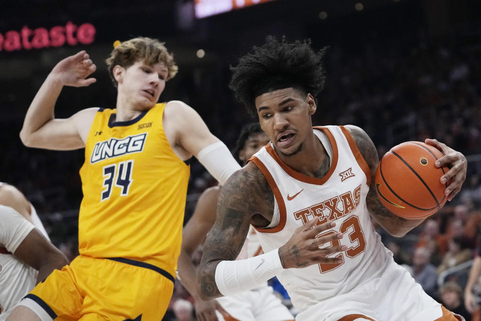 Texas forward Dillon Mitchell (23) grabs a rebound in front of UNC Greensboro forward Domas Kauzonas (34) during the first half of an NCAA college basketball game in Austin, Texas, Friday, Dec. 29, 2023. (AP Photo/Eric Gay)