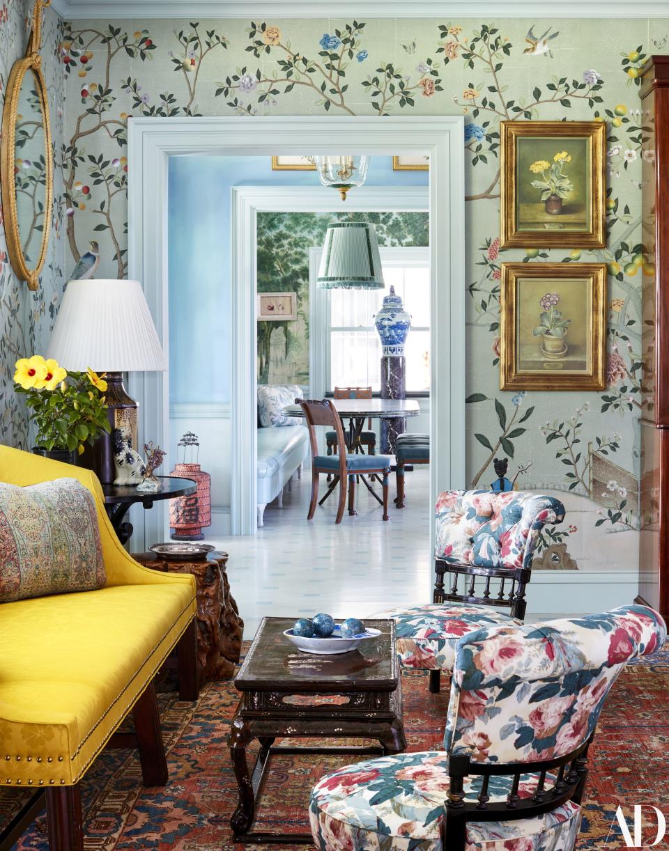 A de Gournay floral festoons the walls of the dining room. Slipper chairs wear a Jasper print