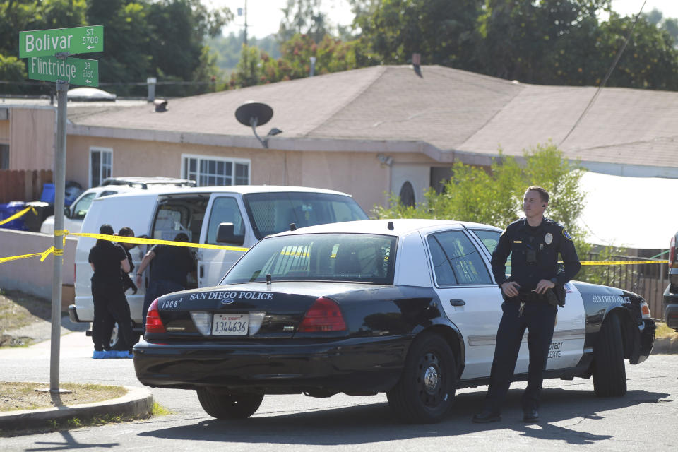 A San Diego Police officer stands in front of a home where two adults and three children died from gunshot wounds during a domestic shooting in the Paradise Hills area in San Diego, Calif., Saturday, Nov. 16, 2019. A husband and wife and three of their young children died Saturday morning at the family's San Diego home in what police believe was a murder-suicide sparked by a bitter divorce. One son is in critical condition. (Hayne Palmour IV/The San Diego Union-Tribune via AP)