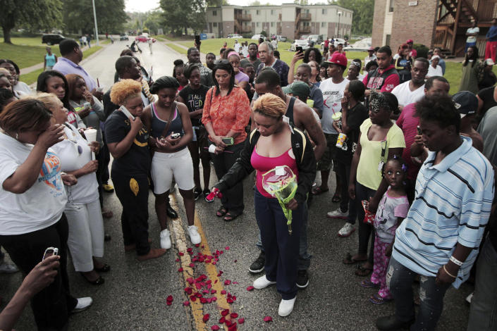 FILE - In this Aug. 9, 2014, file photo, Lezley McSpadden, center, drops rose petals on the bloodstains from her son Michael Brown, who was shot and killed by a police officer in the middle of the street in Ferguson, Mo. (Huy Mach/St. Louis Post-Dispatch via AP, File)
